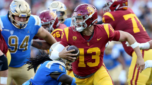 Nov 18, 2023; Los Angeles, California, USA; USC Trojans quarterback Caleb Williams (13) scrambles against UCLA Bruins defensive lineman Carl Jones Jr. (4) during the second quarter at United Airlines Field at Los Angeles Memorial Coliseum.